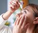 Young woman putting eye drops at home